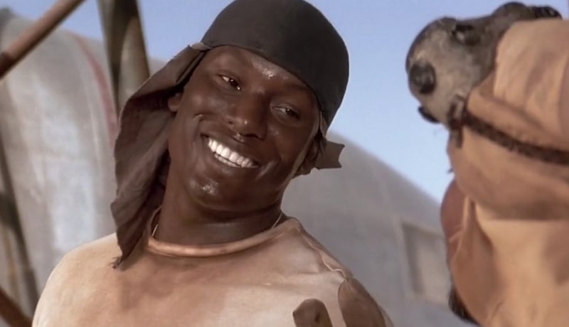 Tyrese smiling with a backwards cap on and a dirty white shirt.