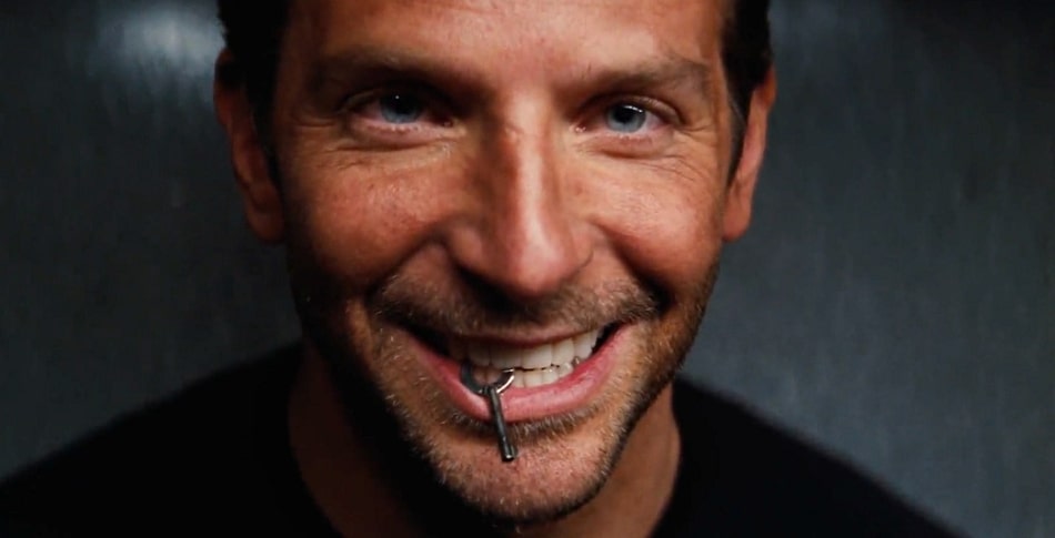 Bradley Cooper smiling with a key in his mouth.
