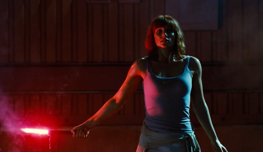 Bryce Dallas Howard as Claire in a red silhouette in the dark holding a flair in Jurassic World.