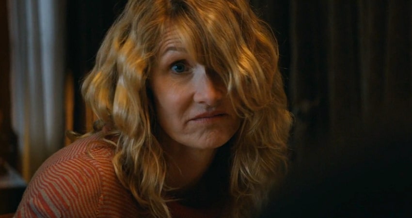 Laura Dern looking puzzled with long blonde hair and orange shirt in Cold Pursuit.
