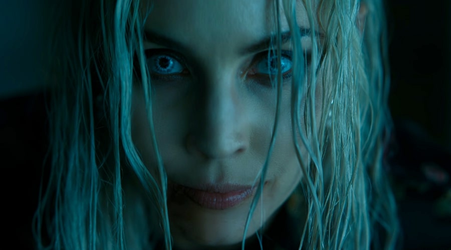 Noomi Rapace with platinum blonde hair and bright blue eyes and pink lips.