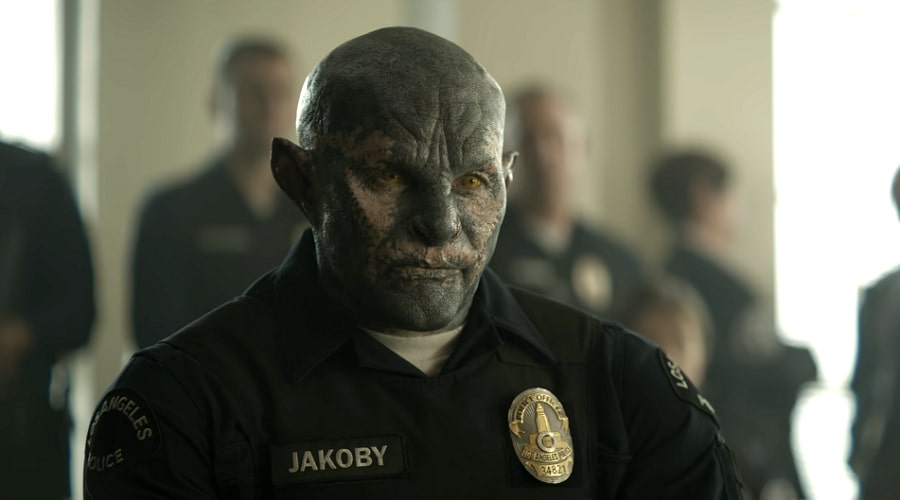 A blue orc named Jakoby wearing a policeman's uniform in a crowded room.