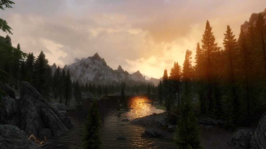 Beautiful Skyrim landscape overlooking a lake and large mountains in the distance.