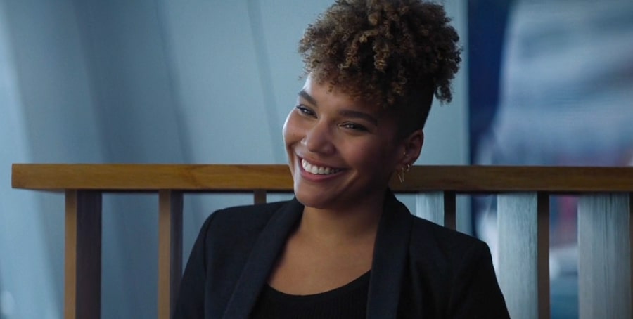 Emmy Raver-Lampman with a beautiful smile in a black suit in Blacklight film.